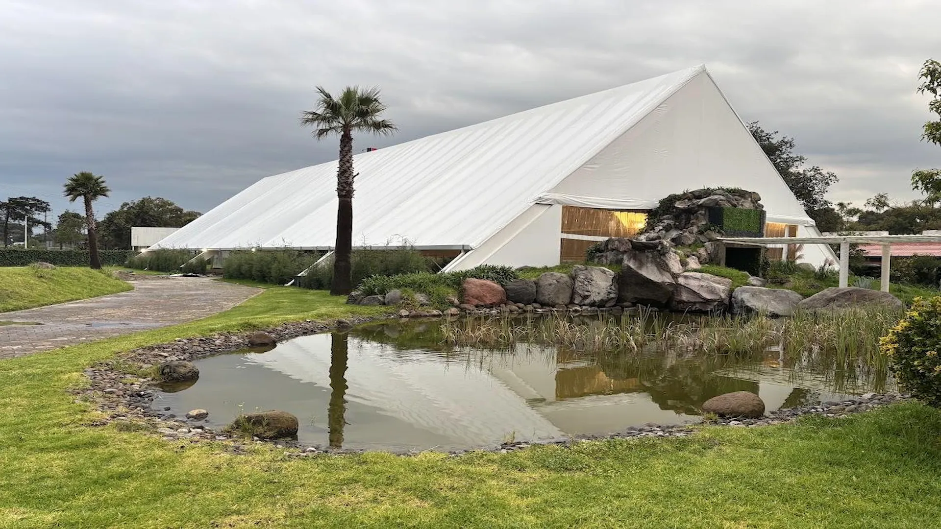 Carpa blanca del jardín con lago y palmeras